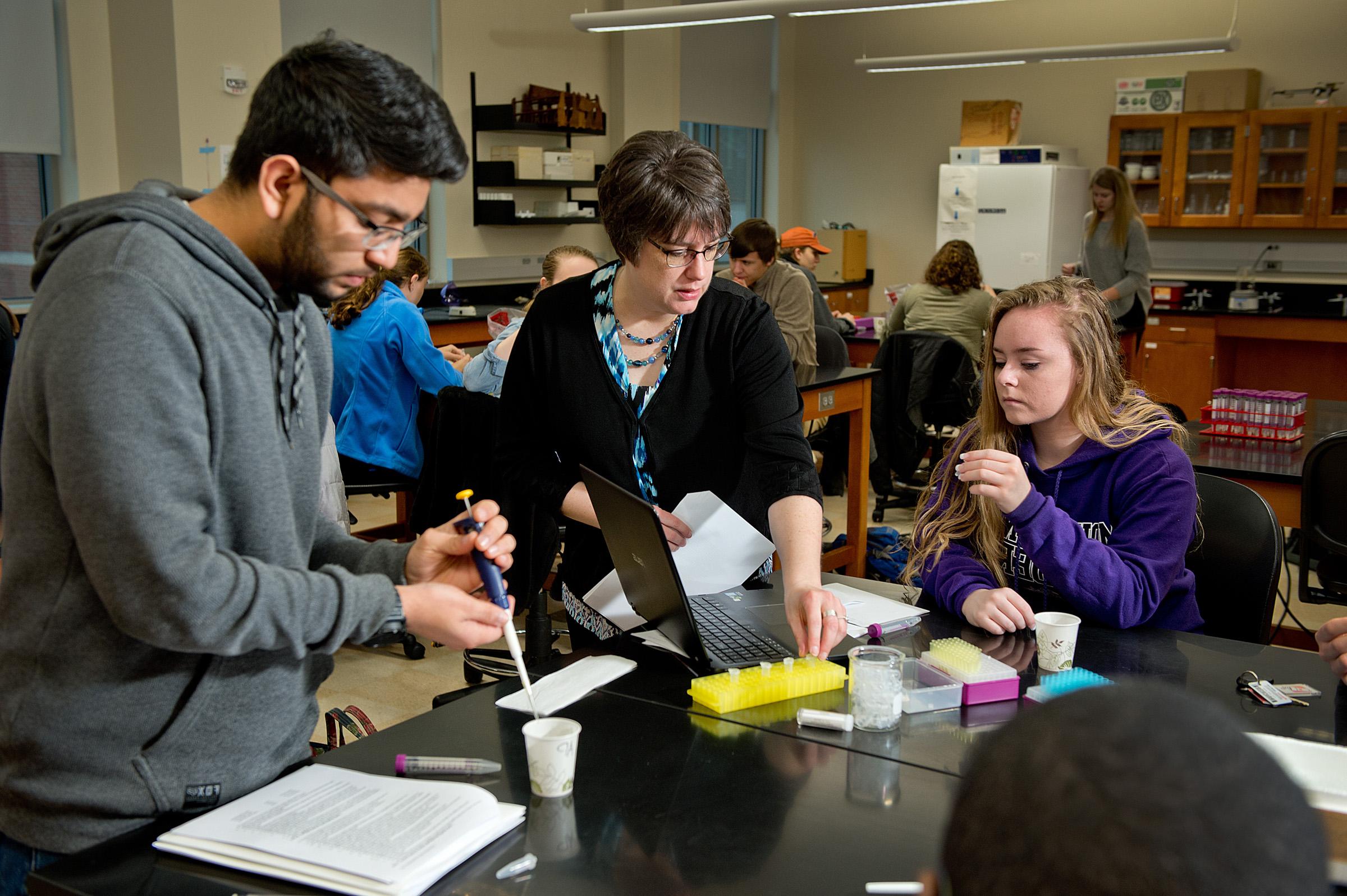 A faculty member assists two students with a lab assignment